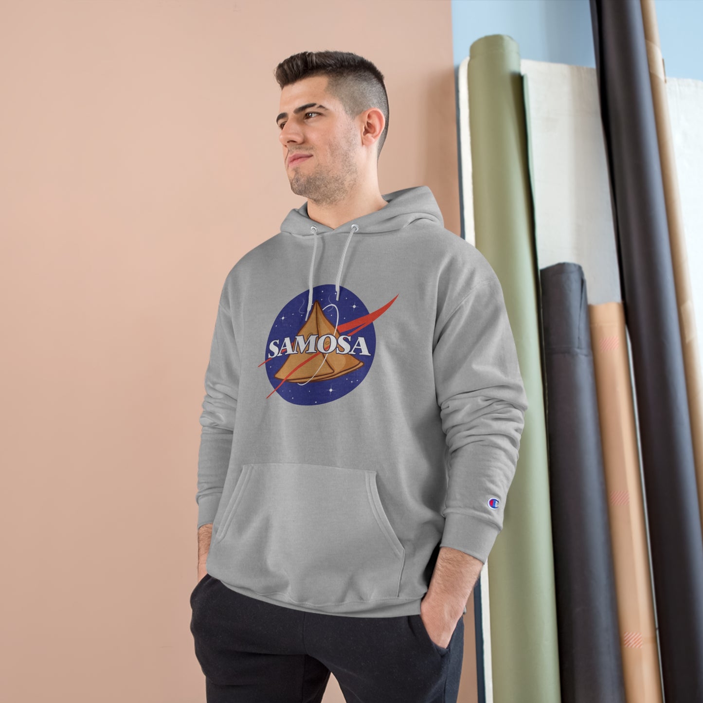Man wearing NASA Samosa Champion hoodie, featuring a quirky space and snack design, in a cozy atmosphere.