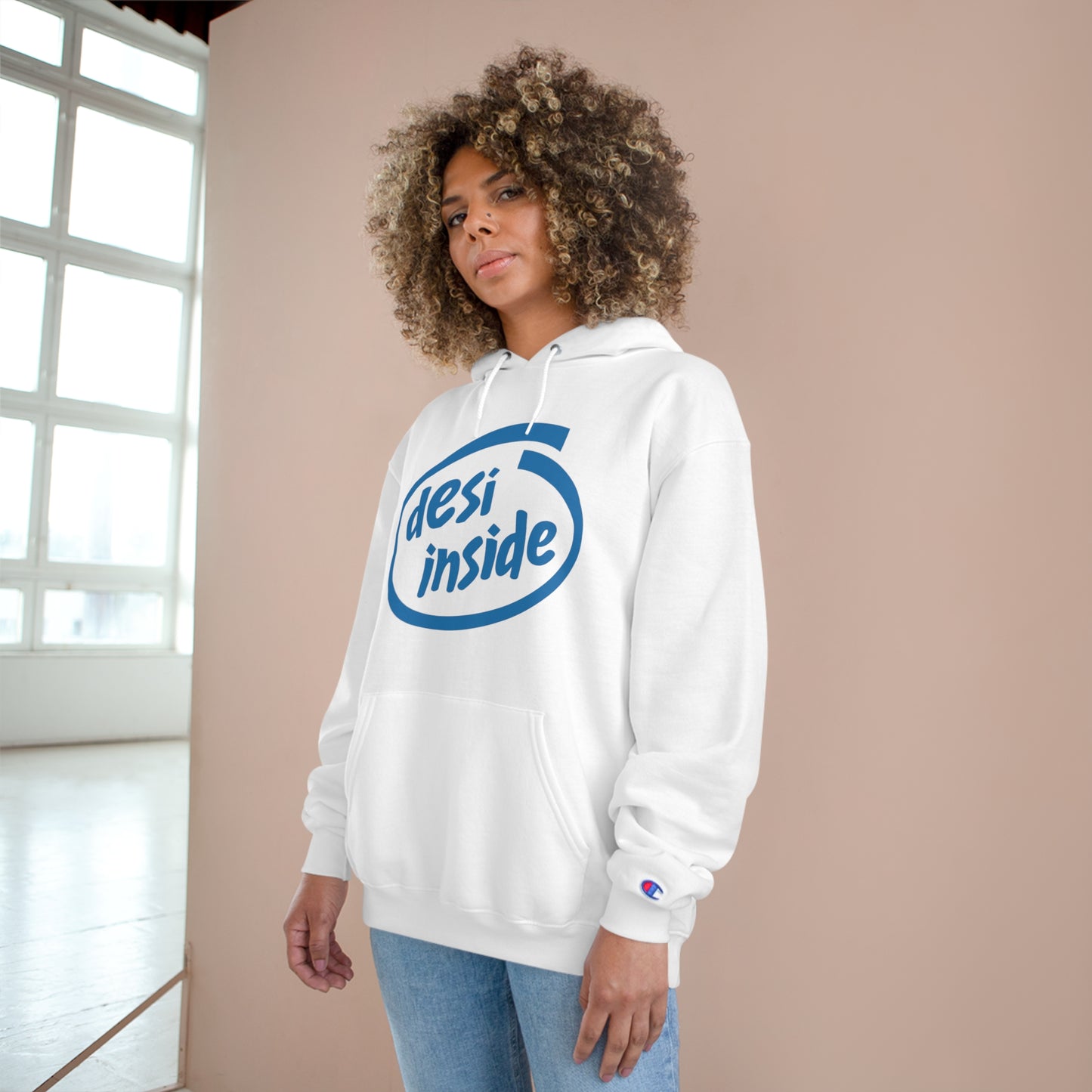 Woman wearing a white 'Desi Inside' Champion hoodie, showcasing cozy style and cultural pride.