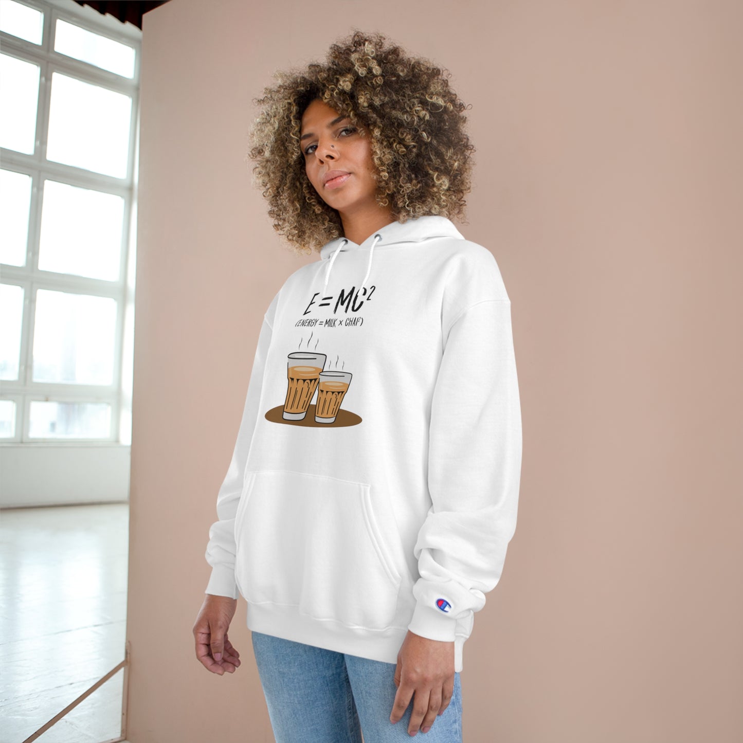 Woman wearing E=M*C Champion hoodie featuring chai graphic and spacious pocket for a cozy look.
