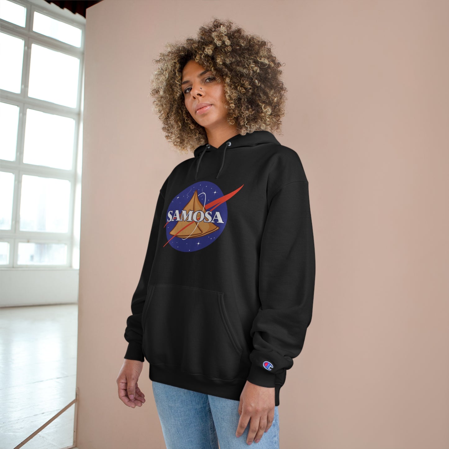 Woman wearing NASA Samosa Champion hoodie, featuring space-themed design and cozy fleece material.