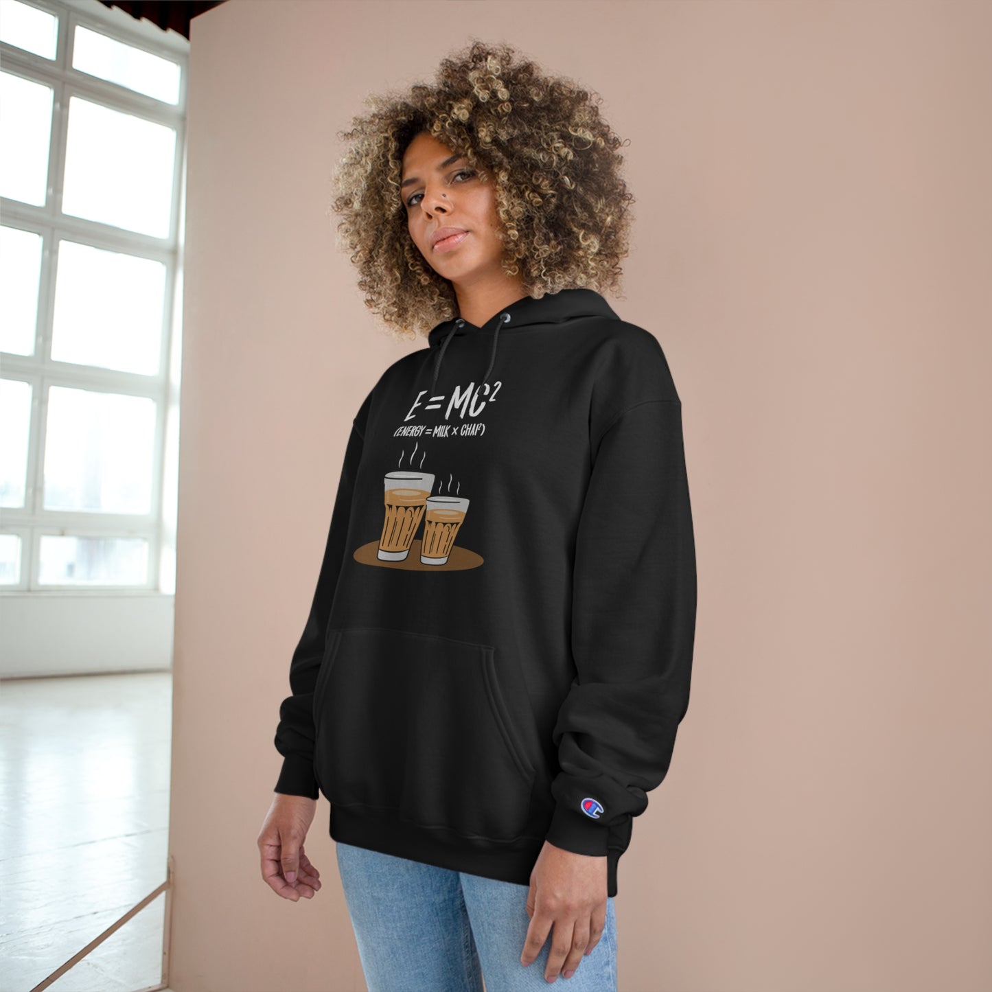 Woman wearing E=M*C Champion hoodie, featuring chai graphic and cozy design, highlighting desi energy formula.