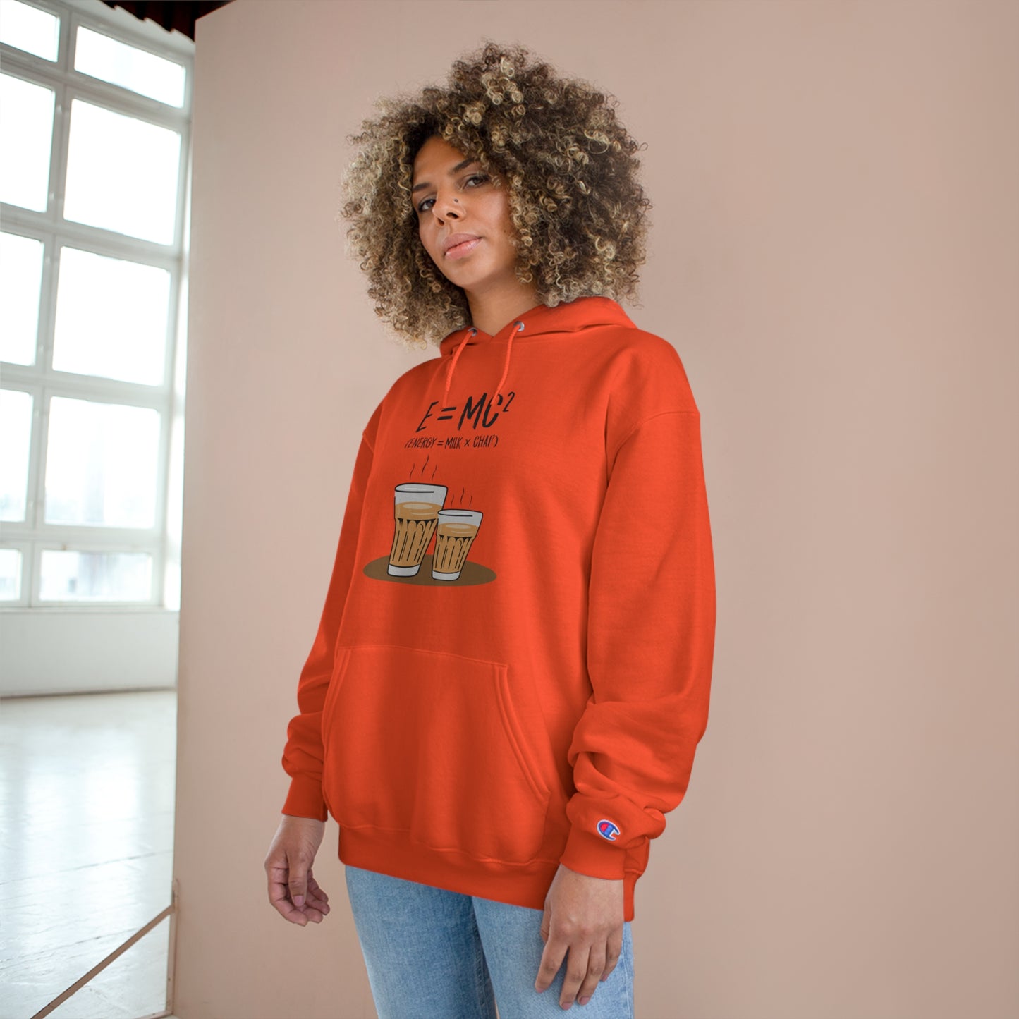 Cozy E=M*C Champion hoodie in vibrant orange, perfect for chai lovers, featuring a graphic of two glasses.