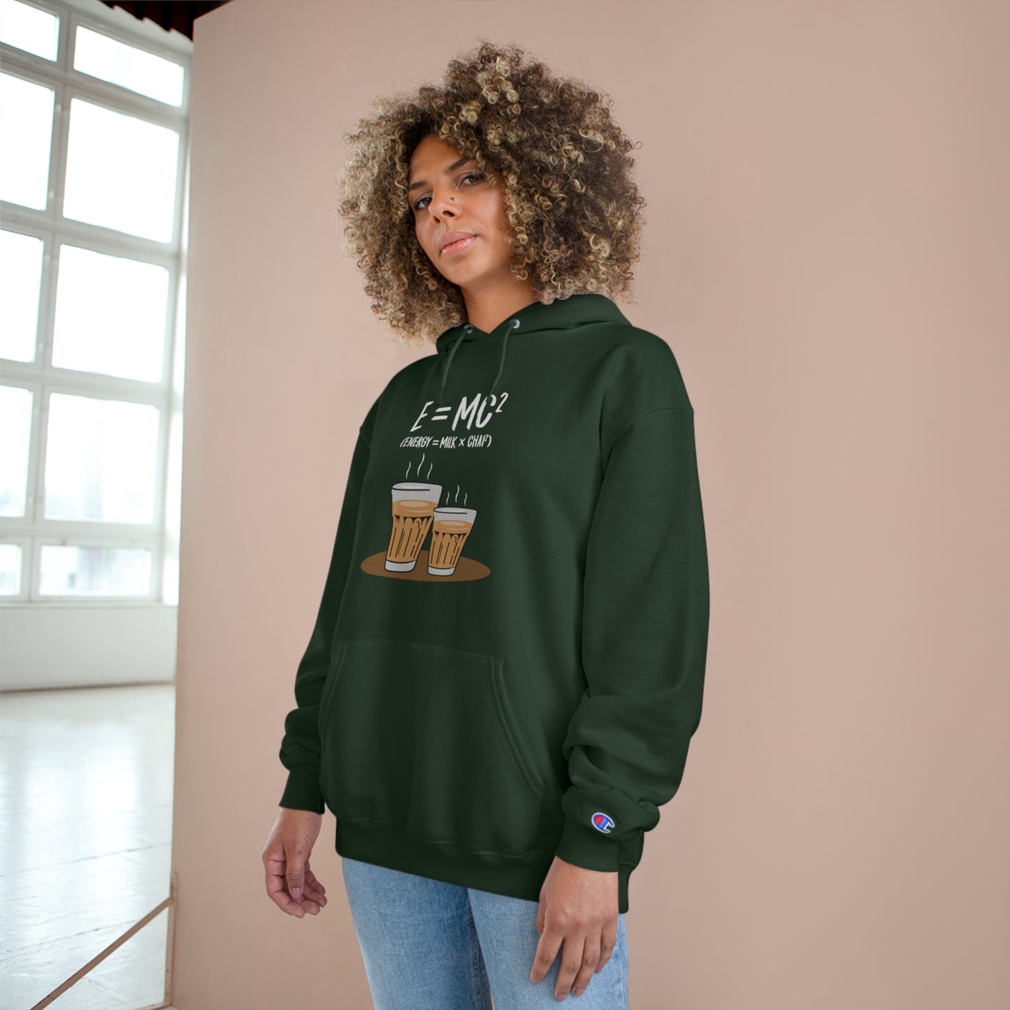Woman wearing an E=M*C Champion hoodie with chai graphic, showcasing comfort and style for chai lovers.